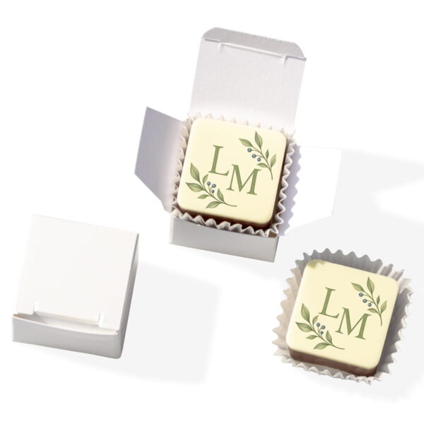 Karree-Fotopraline zur Taufe mit grünem Monogramm LM und Blättermotiv im geöffneten perlmuttweißen Würfel.