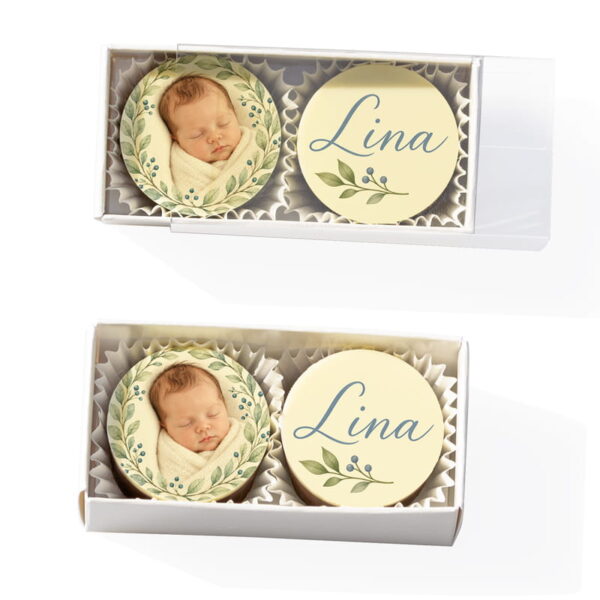 2 Fotopralinen zur Taufe in der Stange. Auf den Pralinen zusehen sind Babyfoto im Blätterkranz und Name Lina mit Zweigmotiv.