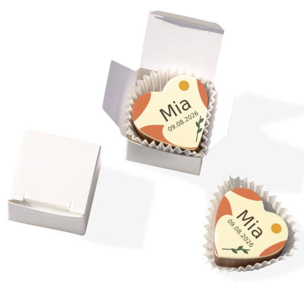 Herzpraline zur Taufe mit Name Mia, Datum und orangefarbenem Motiv im geöffneten perlmuttweißen Würfel.